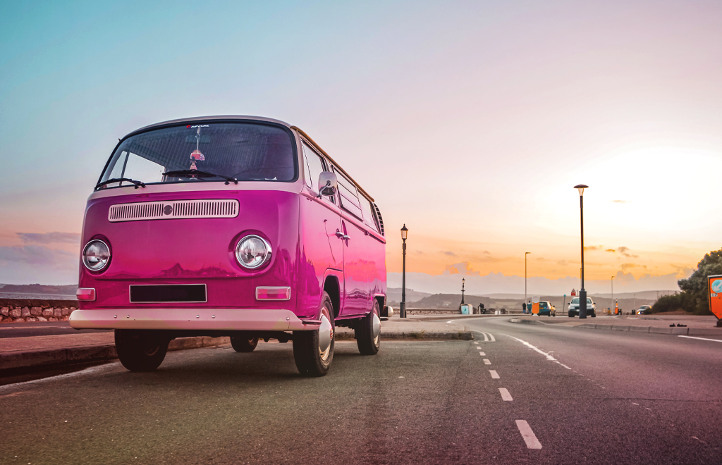 pink camper van parked at the seafront