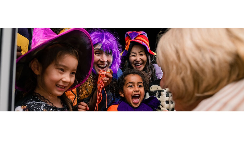 Children dressed in halloween costumes at in the doorway of someone's house