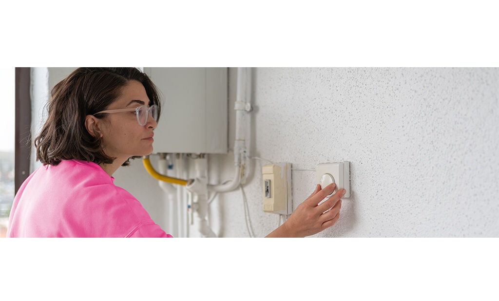 A lady changing the temperature on her thermostat