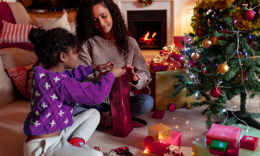 Family wrapping presents under a Christmas tree