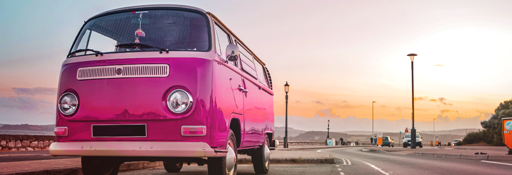 pink camper van parked at the seafront