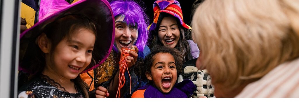 Children dressed in halloween costumes at in the doorway of someone's house