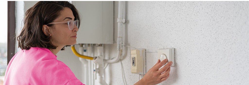A lady changing the temperature on her thermostat